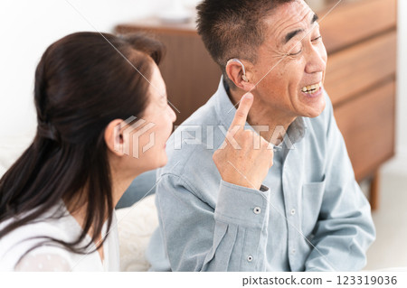A middle-aged man wearing a hearing aid and a happy woman A middle-aged man wearing a hearing aid and a happy woman 123319036