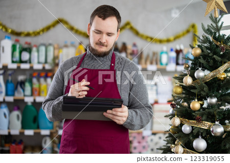 Male salesperson makes notes on an electronic tablet - keeps track of the receipt and expenditure of goods in supermarket Male salesperson makes notes on an electronic tablet - keeps track of the receipt and expenditure of goods in supermarket 123319055