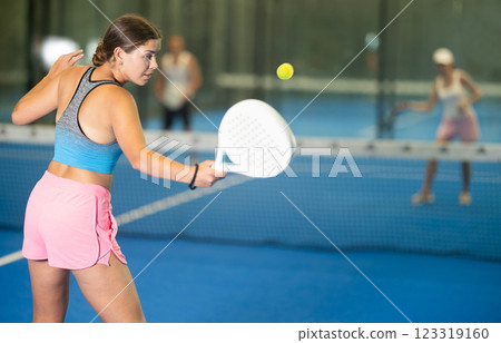 Young woman playing tennis against man and woman Young woman playing tennis against man and woman 123319160