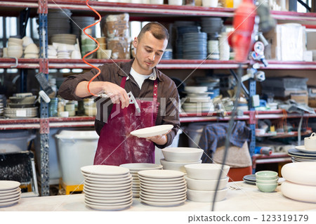 Young man paints blanks of ceramic products Young man paints blanks of ceramic products 123319179