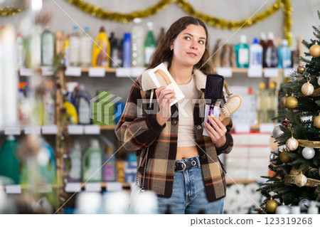 Young female buyer choosing comb in store with New Year decoration Young female buyer choosing comb in store with New Year decoration 123319268