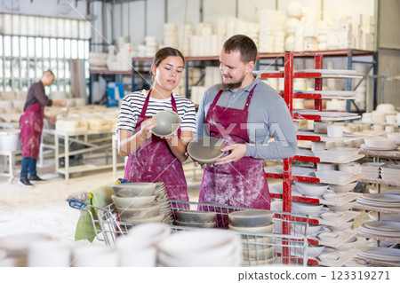 Artisans examining and conferring over crafted wares in workshop 123319271