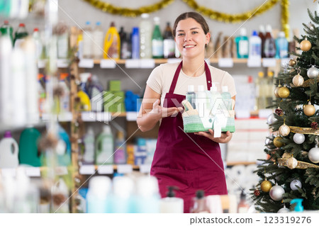 Young saleswoman holding gift basket in supermarket during X-mas Young saleswoman holding gift basket in supermarket during X-mas 123319276