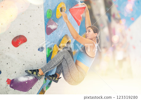 Woman in sportswear practicing rock climbing on climbing wall 123319280