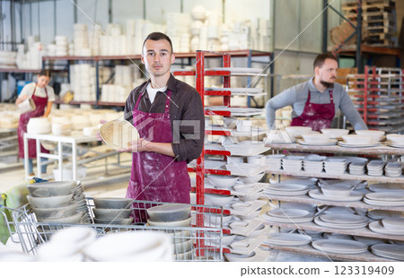 Enthusiastic ceramicist demonstrating handcrafted plates in ceramic studio Enthusiastic ceramicist demonstrating handcrafted plates in ceramic studio 123319409
