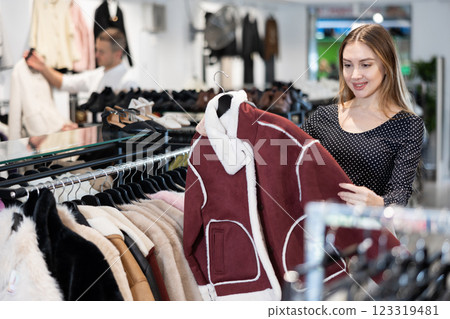 Young woman choosing fur coat in clothing store Young woman choosing fur coat in clothing store 123319481