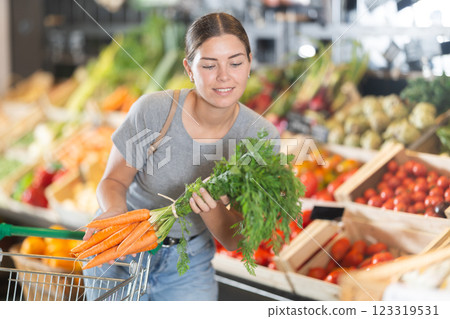 Young girl purchaser buying organic carrot in grocery store 123319531