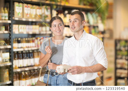 Man with package of eggs in hands talks with wife about buying ingredients for making homemade pie. Man with package of eggs in hands talks with wife about buying ingredients for making homemade pie. 123319540