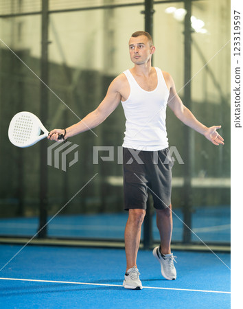 Active man with enthusiasm playing padel on tennis court Active man with enthusiasm playing padel on tennis court 123319597