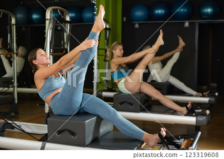 Woman in sports top and leggings doing exercises on reformer 123319608
