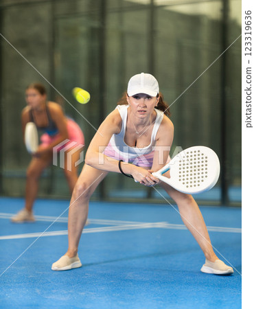 Woman playing padel on open court on summer day. Sport and active lifestyle concept 123319636