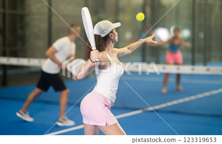 Adult woman and young man playing tennis against woman Adult woman and young man playing tennis against woman 123319653