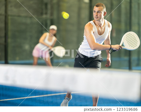 Active man with enthusiasm playing padel on tennis court 123319686
