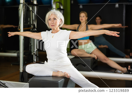 Gray-haired woman sitting on a Pilates platform 123319889