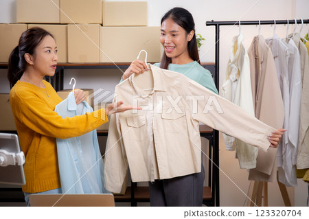 Two young asian woman live online clothing store while showing clothing with tablet on social. Two young asian woman live online clothing store while showing clothing with tablet on social. 123320704