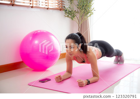 Young asian woman practice workout with posing plank on mat while motivation and determined. Young asian woman practice workout with posing plank on mat while motivation and determined. 123320791