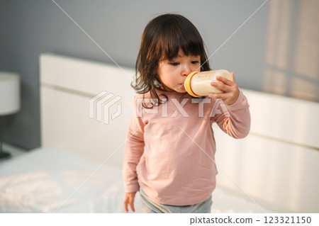 toddler girl drinking milk from bottle on bed toddler girl drinking milk from bottle on bed 123321150