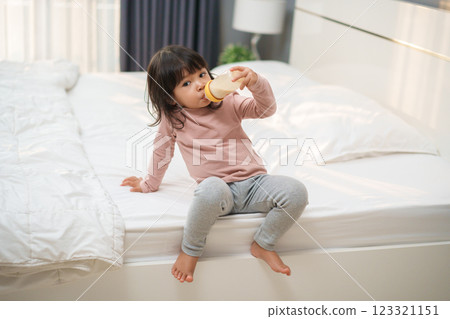 toddler girl drinking milk from bottle on bed toddler girl drinking milk from bottle on bed 123321151