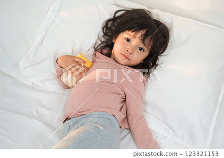 toddler girl drinking milk from bottle on bed 123321153