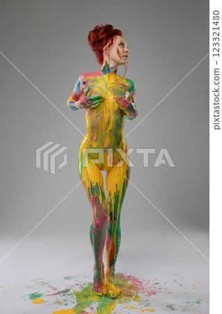 Woman adorned with vibrant body paint strikes an artistic pose in studio 123321480