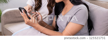 Two friends browsing and discussing shopping options on a mobile phone together Two friends browsing and discussing shopping options on a mobile phone together 123321731