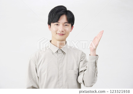 白色背景中，一名 20 多歲的男子用手掌指向右側 123321938