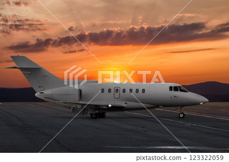 Modern corporate business jet at the airport apron on the background of a picturesque sunset 123322059
