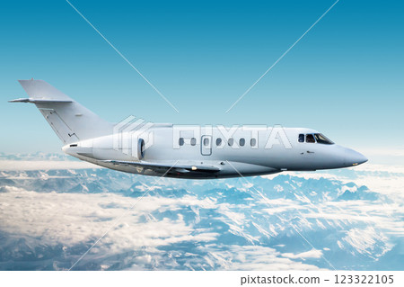 White modern corporate aircraft flies over snow-covered mountains 123322105