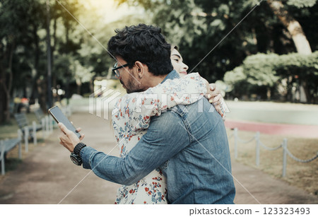 Unfaithful man hugging his girlfriend and looking at the cell phone. Concept of unfaithful man using cell phone. Unfaithful man looking at the cell phone while hugging his girlfriend outdoors Unfaithful man hugging his girlfriend and looking at the cell phone. Concept of unfaithful man using cell phone. Unfaithful man looking at the cell phone while hugging his girlfriend outdoors 123323493