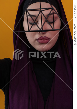 Elegant Muslim woman in a hijab with a geometric structure in a conceptual portrait. Elegant Muslim woman in a hijab with a geometric structure in a conceptual portrait. 123324509