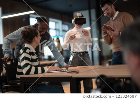 Disabled businesswoman in a wheelchair working in modern coworking office. Team around is using virtual reality goggles, collaborating with the latest technology in an open space startup creative 123324597