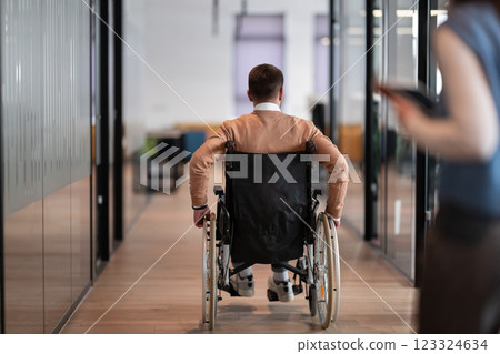 Diverse business team, including a colleague in a wheelchair, walks through a sleek glass office corridor, showcasing inclusion, teamwork, and empowerment in a dynamic modern startup open-space work Diverse business team, including a colleague in a wheelchair, walks through a sleek glass office corridor, showcasing inclusion, teamwork, and empowerment in a dynamic modern startup open-space work 123324634