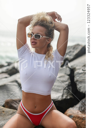A Stylish Woman in Trendy Swimwear and White T-shirt Joyfully Posing Beautifully on the Sunny Beach A Stylish Woman in Trendy Swimwear and White T-shirt Joyfully Posing Beautifully on the Sunny Beach 123324957