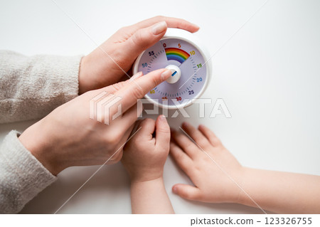 Female adult and child interaction with kitchen timer on white surface 123326755