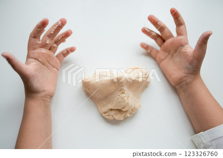 Child hands playing with soft dough on white background 123326760