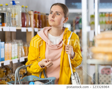 Young woman with basket of food in grocery store Young woman with basket of food in grocery store 123326964