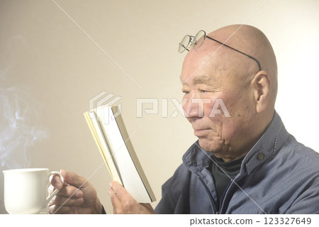 微笑的老人一邊喝著熱氣騰騰的飲料一邊讀書 微笑的老人一邊喝著熱氣騰騰的飲料一邊讀書 123327649