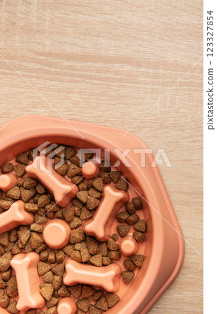 Slow feeder dog bowl filled with dry dog food on wooden table Slow feeder dog bowl filled with dry dog food on wooden table 123327854