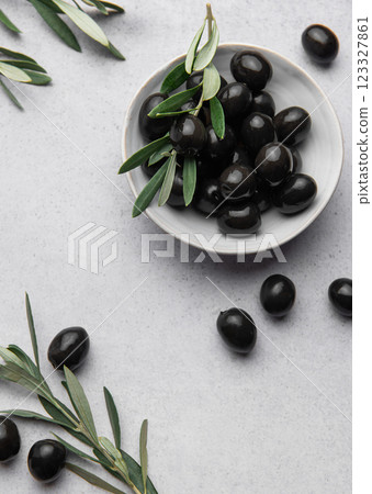 Black olives with olive branches served in ceramic bowl on gray background 123327861