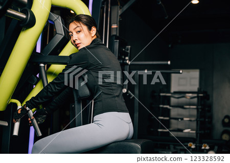 Portrait of beautiful Asian young woman performing squats on a gym machine, female working out with rowing machine at crossfit fitness, healthy lifestyle concept 123328592