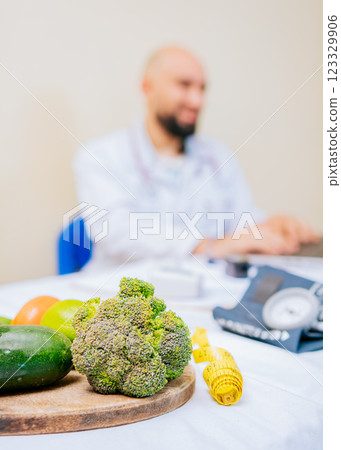 Focus on vegetables of nutritionist with laptop at the desk. Nutritionist working on laptop, giving online consultation to client at clinic, focus on vegetables Focus on vegetables of nutritionist with laptop at the desk. Nutritionist working on laptop, giving online consultation to client at clinic, focus on vegetables 123329906