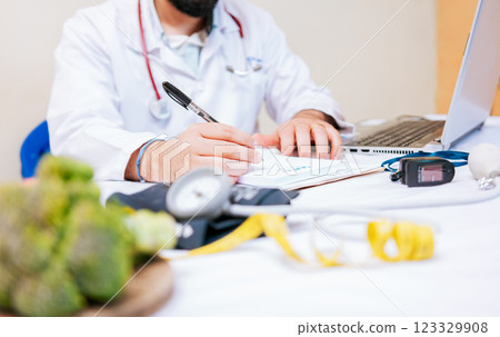 Close-up of nutritionist writing on notepad. Hands of male nutritionist taking notes at his desk, Nutritionist hands taking medical records in the office Close-up of nutritionist writing on notepad. Hands of male nutritionist taking notes at his desk, Nutritionist hands taking medical records in the office 123329908