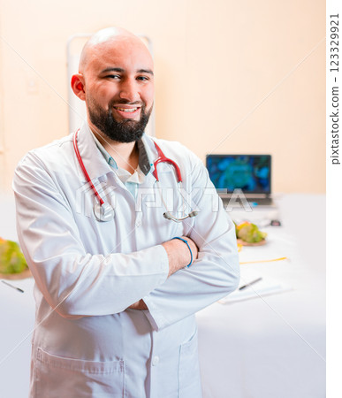 Smiling nutritionist doctor with crossed arms in her office. Portrait of smiling professional nutritionist, Portrait of smiling male nutritionist at his workplace Smiling nutritionist doctor with crossed arms in her office. Portrait of smiling professional nutritionist, Portrait of smiling male nutritionist at his workplace 123329921
