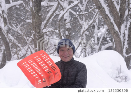 一位老人在雪地裡清理積雪 一位老人在雪地裡清理積雪 123330896