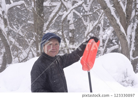 一位老人在雪地裡清理積雪 一位老人在雪地裡清理積雪 123330897
