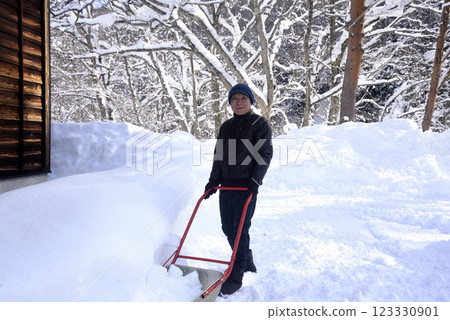 An old man clearing snow using a snow dump in a snowy area 123330901