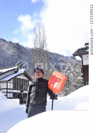 A smiling old man using a snow plow to remove snow in a snowy area 123330912