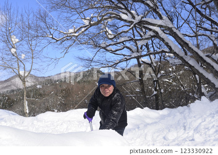 A smiling old man using a snow plow to remove snow in a snowy area 123330922