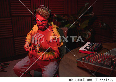 Man vocal artist singing in a recording studio with guitar copy space. Male singer singing a song and playing guitar. Sound record and music streaming concept Man vocal artist singing in a recording studio with guitar copy space. Male singer singing a song and playing guitar. Sound record and music streaming concept 123331399