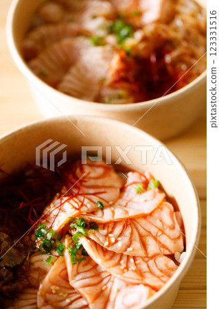 Donburi with sliced salmon on sushi rice in paper container. Healthy take away food. 123331516